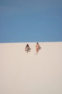 Duas visitantes descem uma duna branca quase vazia nos Lençóis Maranhenses fora da alta temporada