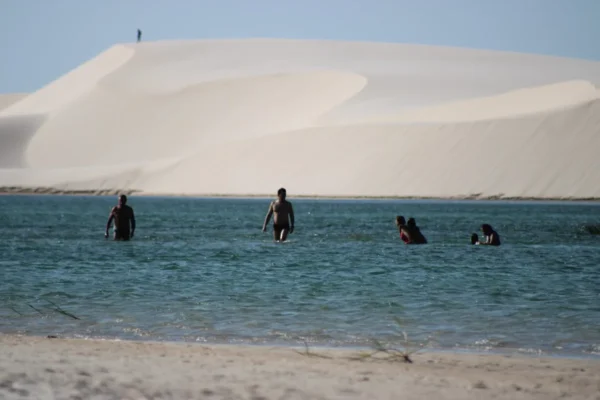 Turistas tomando banho em lagoa de água doce durante tour guiado pelo Parque Nacional dos Lençóis Maranhenses