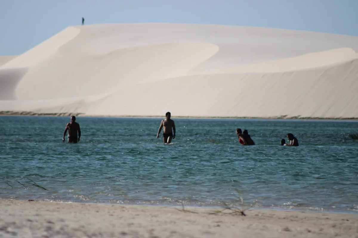 Turistas tomando banho em lagoa de água doce durante tour guiado pelo Parque Nacional dos Lençóis Maranhenses